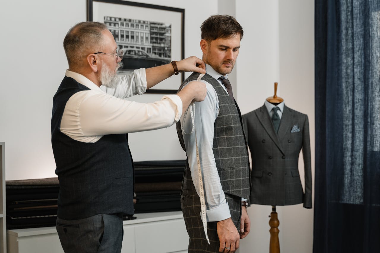 our-services-3 Tailor expertly measuring client for a custom-made suit in a stylish workshop.