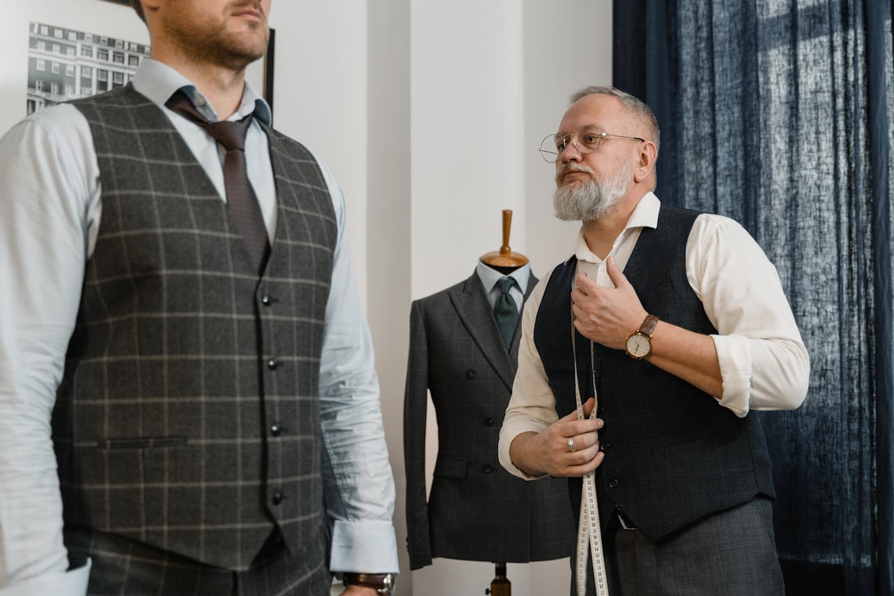 our-services-2 Tailor measuring client for custom suit fitting in a professional setting.