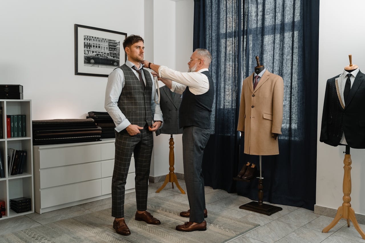 gallery-6 Experienced tailor adjusting a young mans stylish suit in a sophisticated atelier setting.
